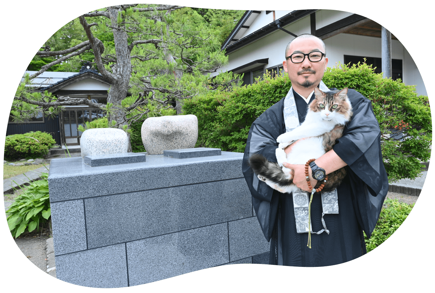 長岡 寺泊 町軽井にある、浄土真宗 本願寺派 常禅寺のペットの供養墓の前に愛猫とたたずむ旭住職の様子。